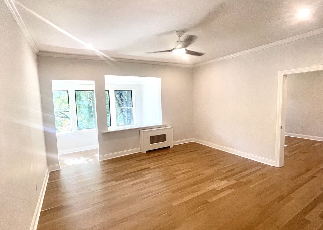 The same living room finished, with a bay window nook and refinished hardwood floors