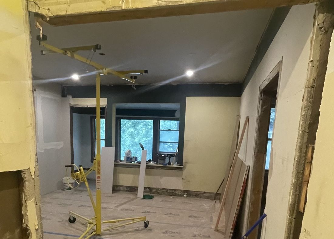 Living room mid-renovation with drywall lift and protected floors