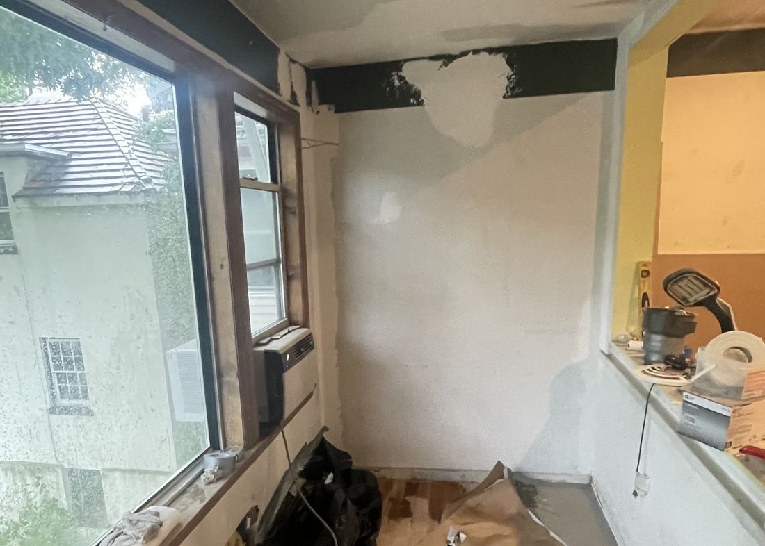 Sun room during demolition with the old window and debris on the floor