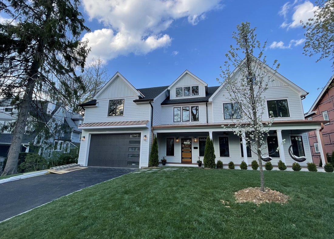The same property after a complete rebuild — new white farmhouse with copper roof detail
