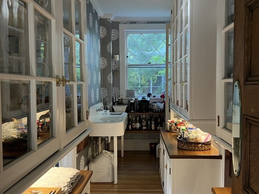 Butler's pantry with glass-front cabinetry, farmhouse sink and wood counters