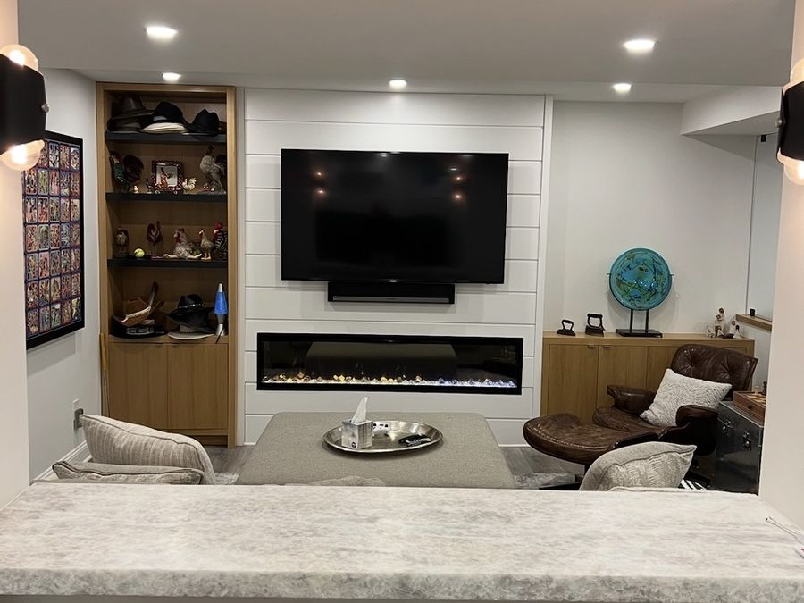Finished basement family room with linear fireplace, shiplap wall and stone bar