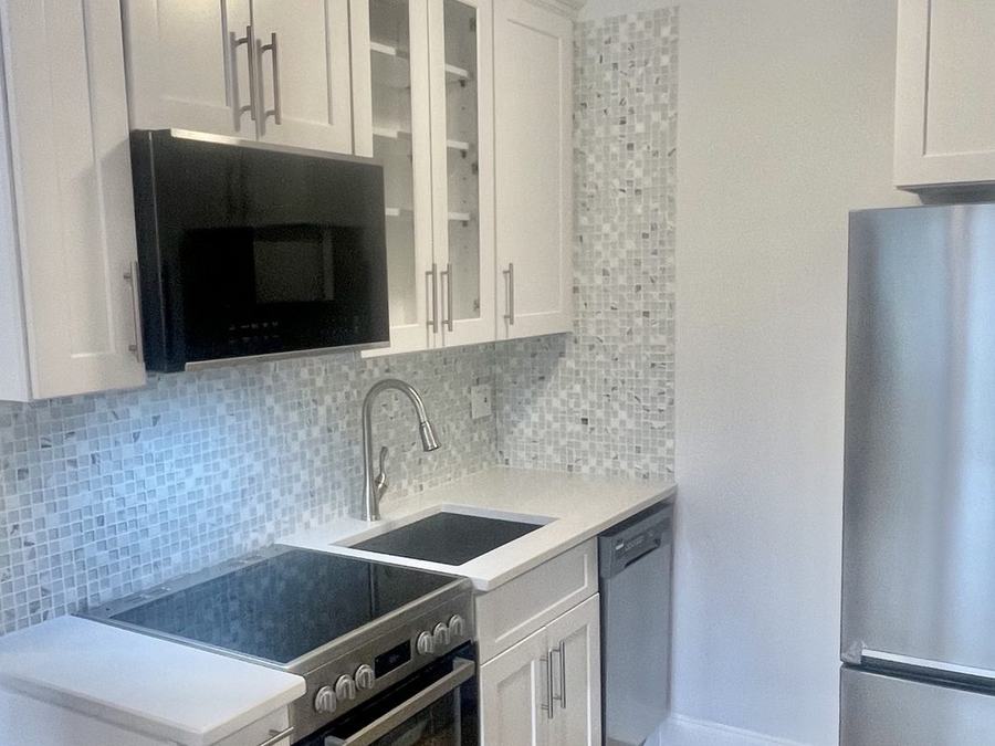 Renovated kitchen with white cabinets and stainless appliances