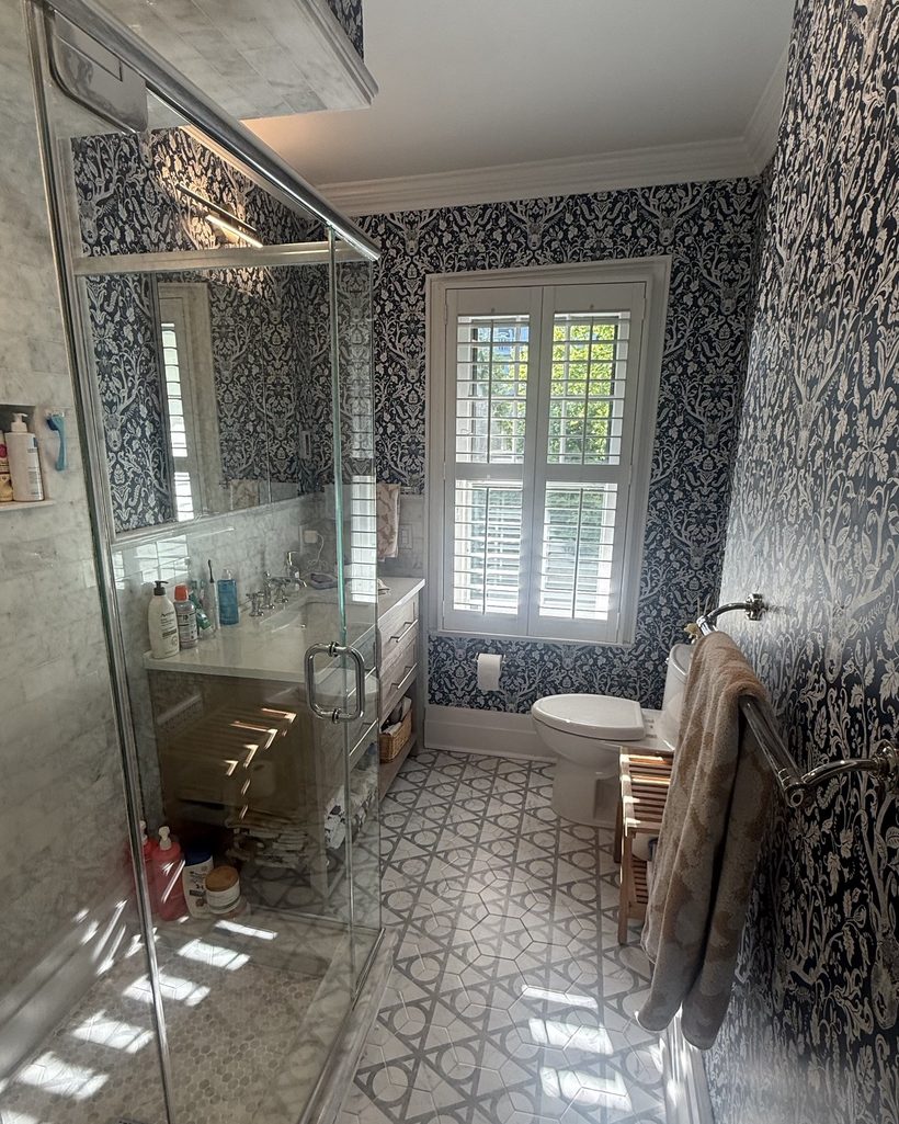 Renovated bathroom with marble tile, patterned stone floor and custom wallpaper