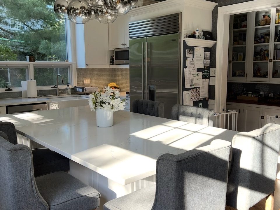 Renovated kitchen with a quartz island, chrome pendant lighting and built-in refrigeration