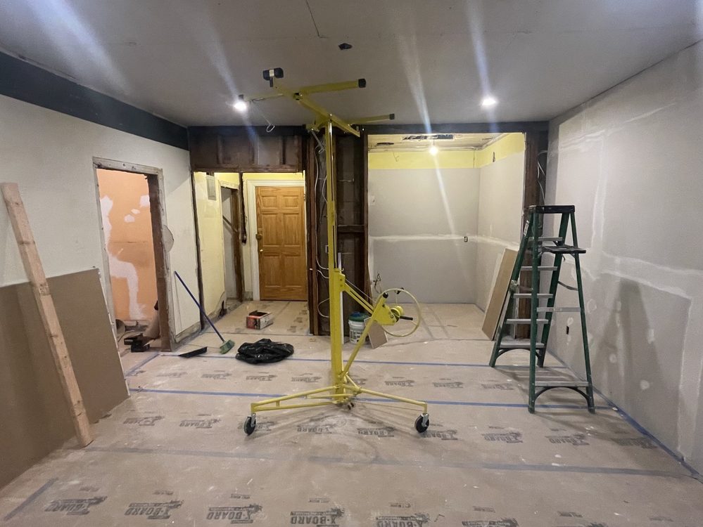 Interior wall and ceiling repair in progress with drywall lift and protected floors